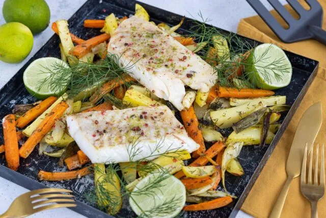 Tavă cu legume coapte de toamnă, scoasă proaspăt din cuptor, pe o masă de lemn