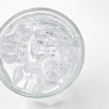 Gutieră dentară transparentă pentru protecția dinților pe timpul nopții, așezată lângă cutia ei