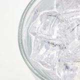 Pahar cu apă rece și cuburi de gheață, băutură care poate declanșa durerea la dinții sensibili